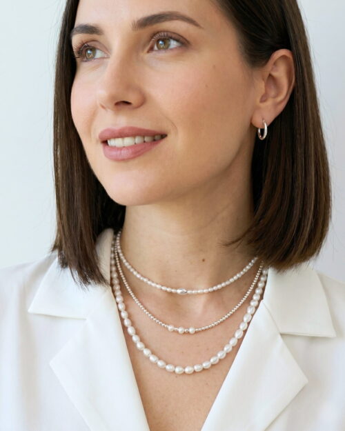 Mujer con el Collar LUA de Plata de Ley 925 y perlas naturales combinado con otros collares AULINE