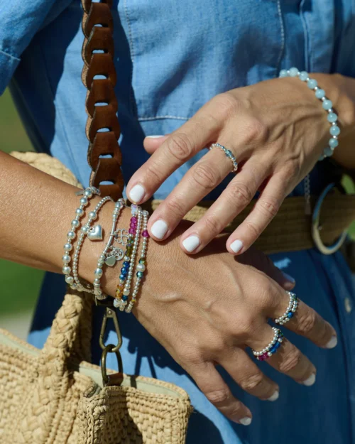 Mujer luciendo varias pulseras de plata 925 y cristales de colores, entre ellas el Set Trío Iris de AULINE