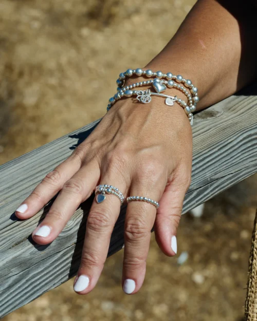 Mujer luciendo anillos de bolas de plata de ley 925 en diferentes dedos, combinados con pulseras de AULINE