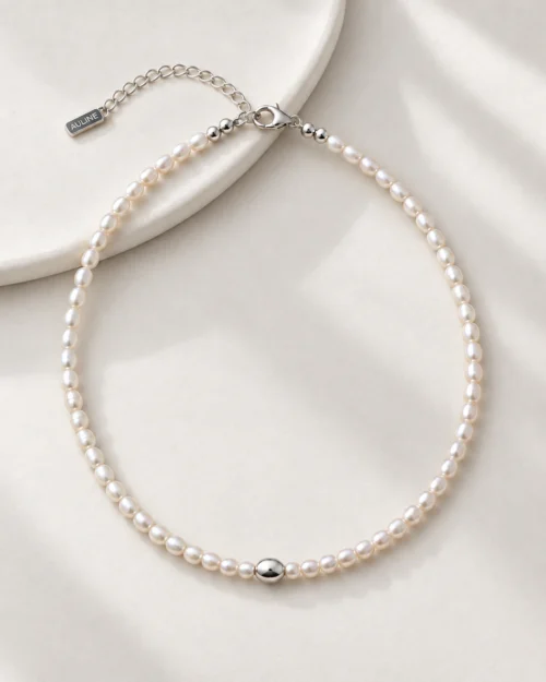 Collar choker Alba de perlas naturales barrocas con detalle central ovalado de plata de ley 925, sobre fondo color crema con tela satinada.