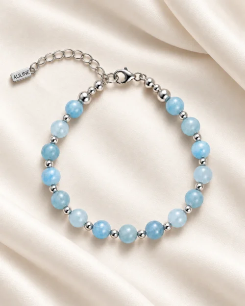 Pulsera Riviera de bolas de aguamarina azul claro y detalles de plata de ley 925, sobre tela satinada color crema