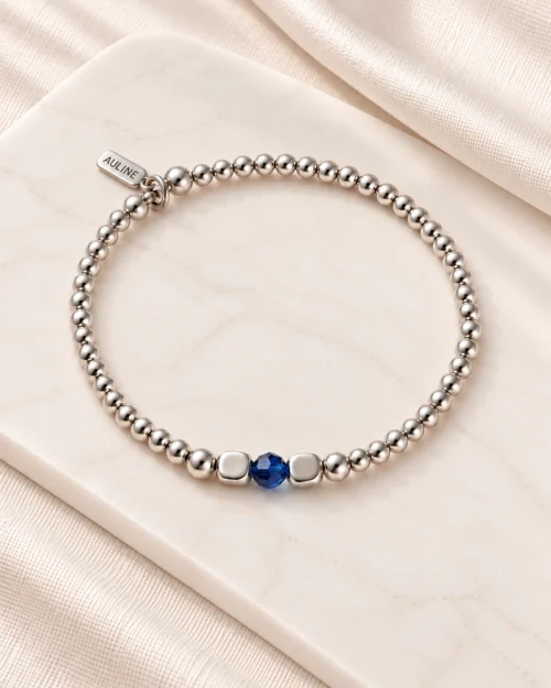 Pulsera Singular de bolas de plata de ley 925 con cristal Preciosa® azul central, sobre base color crema con tela satinada