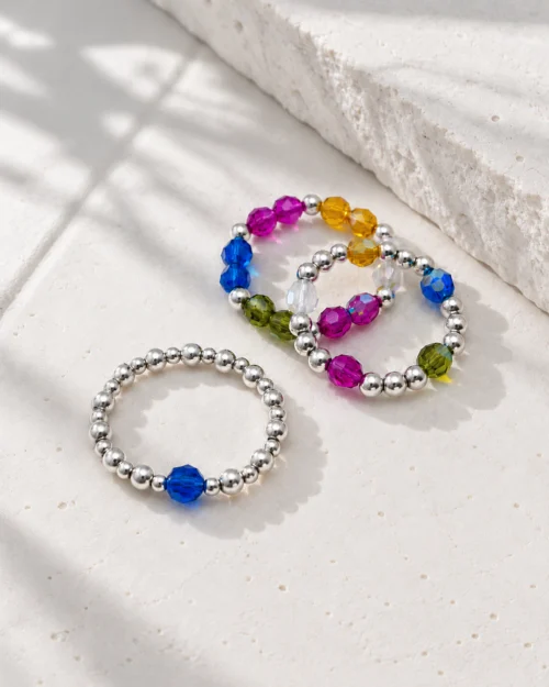 Set Trío Iris de tres anillos de plata de ley 925 con cristales Preciosa® azules y multicolor, sobre fondo de piedra clara